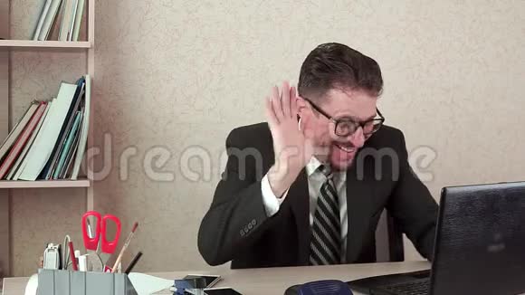 办公室经理带胡须和眼镜的人通过笔记本电脑的视频链接交谈视频的预览图