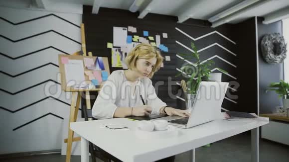 女设计师在一台带有平板电脑的笔记本电脑上工作视频的预览图