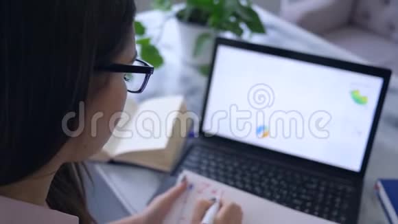 工作项目女商人使用笔记本电脑用记号笔在带图表的笔记本上写笔记视频的预览图