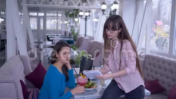吃饭计划戴眼镜的女孩在咖啡馆里为女朋友提供健康早餐时的蔬菜饮食视频的预览图