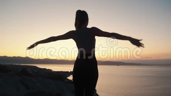 女性练习瑜伽和日出时做伸展运动的剪影视频的预览图