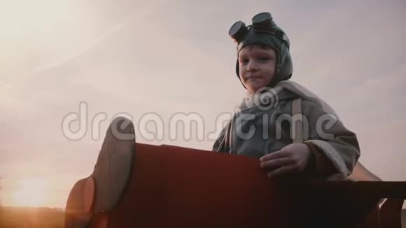 快乐认真的小飞行员男孩穿着有趣的纸板飞机飞行员服装看着相机跑出去慢动作视频的预览图