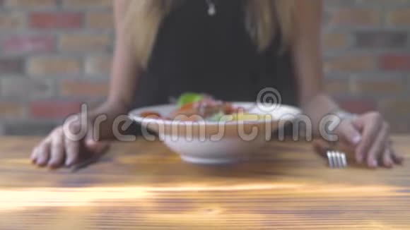 年轻女子在餐厅的木桌上吃意大利面食和红蟹女孩用传统面食视频的预览图