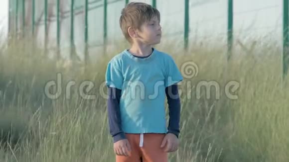 难民小男孩同情地看着高高的篱笆铁丝网肮脏的无家可归的孩子脸上的痛苦视频的预览图