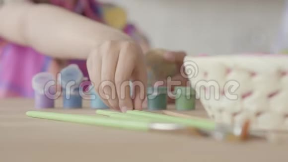 小的丙烯酸涂料瓶和刷子躺在桌子上靠近小女孩的手把刷子放在视频的预览图