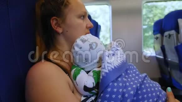 一位年轻的母亲坐着电动火车把婴儿抱在怀里近距离射击视频的预览图