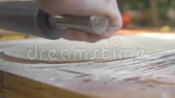 在木桌上用擀薄面团做新鲜面食厨师用擀面杖做馅饼或蛋糕视频的预览图