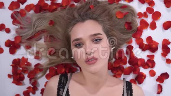 一个年轻女孩的肖像上面有一个刺红色的玫瑰花瓣靠近慢动作视频的预览图