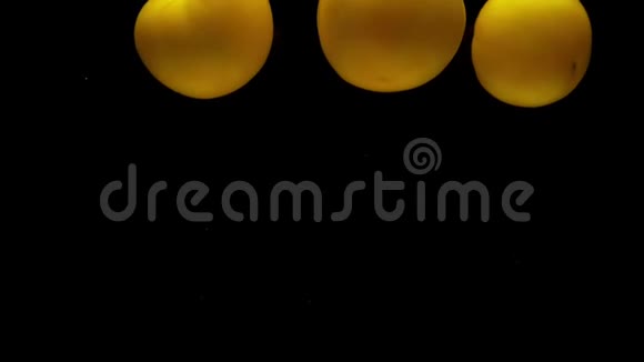 三个黄色的假名躺在透明的水里黑色的背景视频的预览图