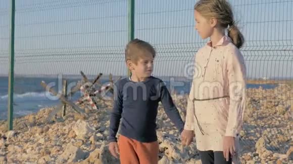 两名贫穷的难民儿童站在战争冲突地区的海边等待获救的男孩和女孩视频的预览图