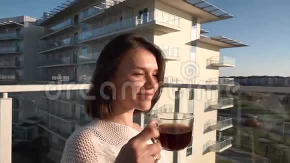 一个年轻漂亮的女孩在酒店的阳台上喝咖啡慢动作视频的预览图