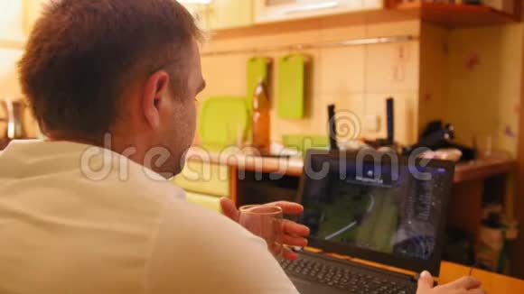 人在电脑上玩电脑游戏从杯子里喝啤酒近距离射击视频的预览图
