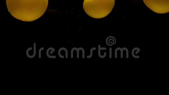 三个黄色的假名躺在透明的水里黑色的背景视频的预览图