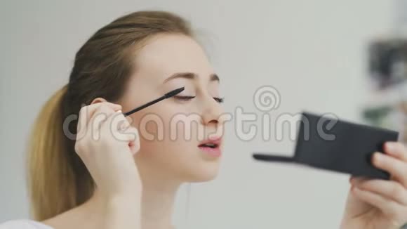 女人用黑色睫毛膏做眼妆看着镜子视频的预览图