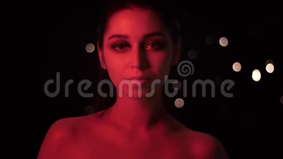 漂亮性感女性的特写镜头配上红色霓虹灯和bokeh背景摆在面前视频的预览图