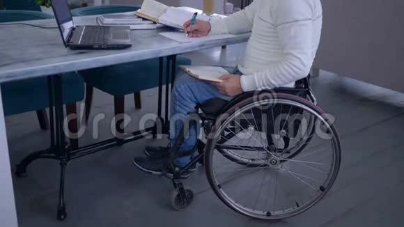 在网上教育的远程学习过程中轮椅上的成功患病学生在手提电脑上工作视频的预览图
