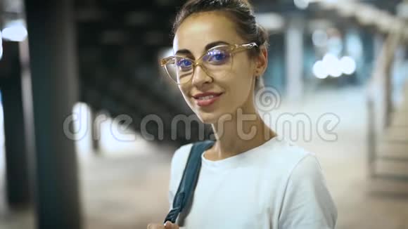 年轻的微笑时尚的美女穿着透明的眼镜摆在户外的特写肖像慢动作视频的预览图
