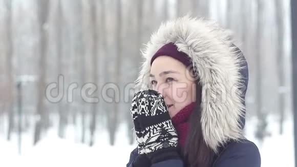 美丽的年轻女孩在一个浪漫的心情揉她的手温暖他们而行走在一个冬季公园视频的预览图