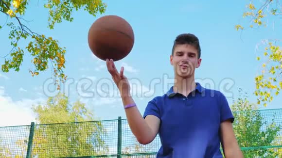 一个十几岁的年轻人在篮球场上把球旋在手指上视频的预览图