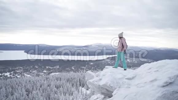 迷人的女人站在白雪皑皑的山边向前看视频的预览图