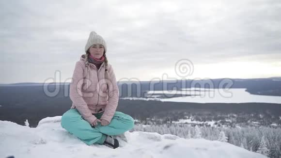 可爱的女人坐在雪地上张开双臂视频的预览图