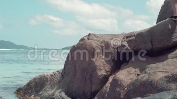 塞舌尔普拉斯林岛一群面目全非的人站在海里的岩石上美丽的海景蓝色干净视频的预览图