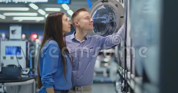 电器商店的男女青年选择买洗衣机回家打开门看着鼓视频的预览图