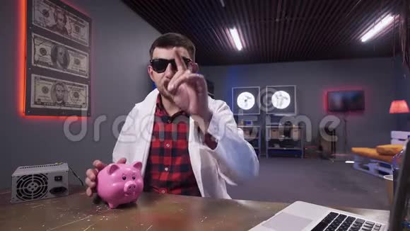 戴墨镜和实验室外套的成熟男人说有猪和笔记本电脑视频的预览图