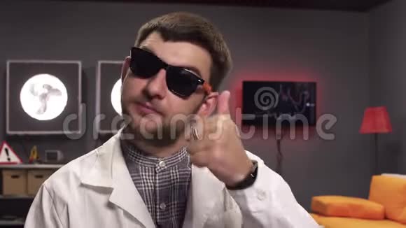 戴着太阳镜和白色实验室外套的英俊留胡子的家伙竖起大拇指视频的预览图