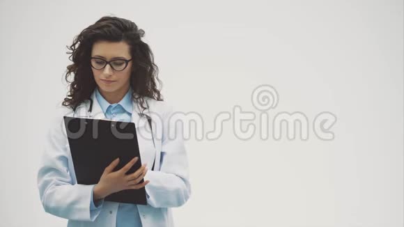 一个微笑的女医生一个站着一个文件夹微笑的女人是医生在这段时间里它是灰色的视频的预览图