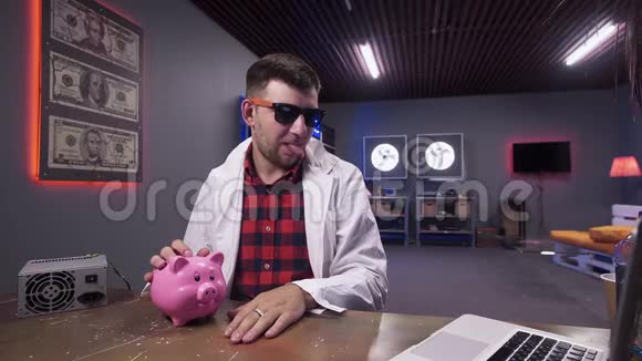 戴墨镜和实验室外套的搞笑家伙说桌子上有猪和笔记本电脑视频的预览图