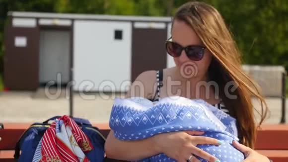 年轻的母亲正在拉着她的孩子抱着他坐在长凳上家庭母亲和人民视频的预览图