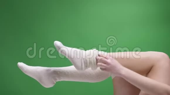 在可爱的白袜子中的少女腿的特写镜头嬉戏地移动背部孤立在绿色上女孩把视频的预览图