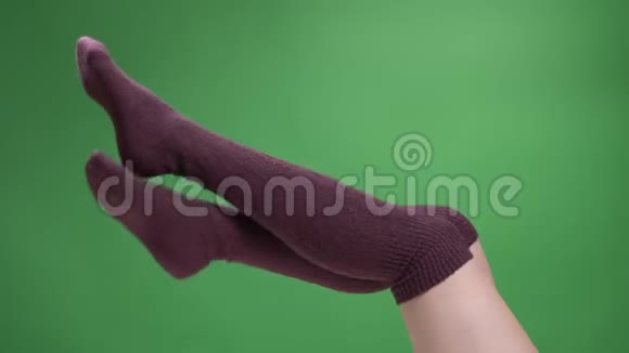 特写侧景拍摄女青少年腿在可爱的红色袜子轻轻移动背部孤立在绿色视频的预览图