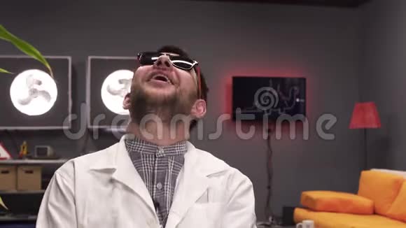 可爱的年轻男性戴着太阳镜和白色的实验室外套快乐地笑着视频的预览图
