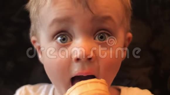 一个饥饿的小男孩的肖像他在华夫饼杯里品尝着白色香草冰淇淋脸上沾满了冰视频的预览图
