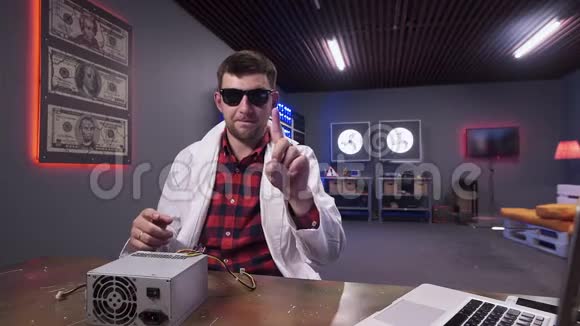 穿着白色实验室外套的深色头发的男人在坐在办公桌后面的镜头前移动手指视频的预览图