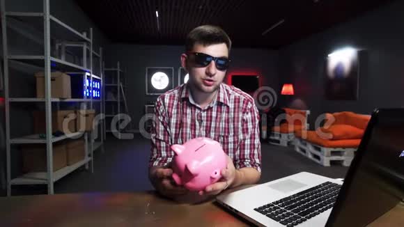 戴着墨镜的年轻人手里拿着塑料猪说话看着镜头视频的预览图
