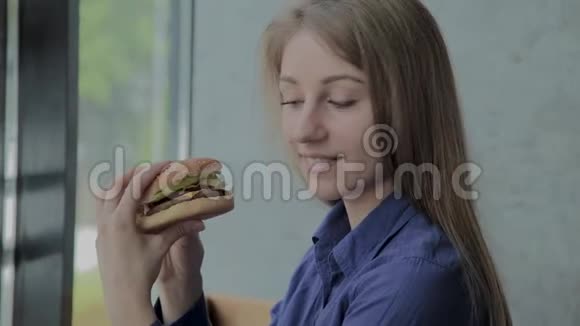 漂亮的女孩手里拿着汉堡快餐店视频的预览图