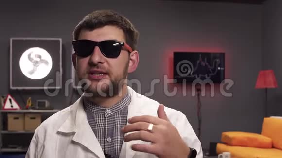 可爱的男人带着太阳镜和白色的实验室外套兴高采烈地说话视频的预览图