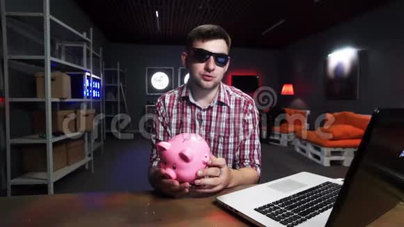 有魅力的人戴着墨镜手里拿着塑料猪说话看着镜头视频的预览图