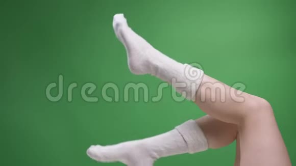 特写侧景拍摄女青少年腿在可爱的短白袜子快乐地移动与背部孤立的绿色视频的预览图