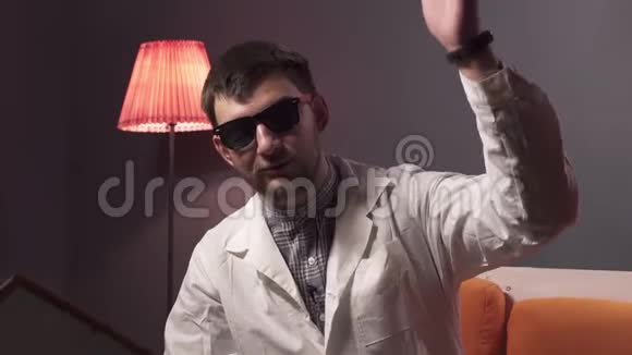 长着胡子戴着太阳镜和实验室外套的聪明男人解释了一些事情视频的预览图