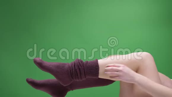 穿着可爱的红袜子的少女腿的特写镜头嬉戏地移动着背部被隔离在绿色上女孩把视频的预览图