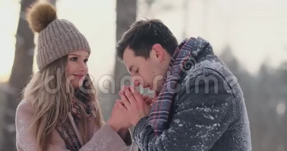 一对相爱的夫妻一个男人用呼吸温暖他的手一个女人冬天在公园里散步的时髦情侣视频的预览图
