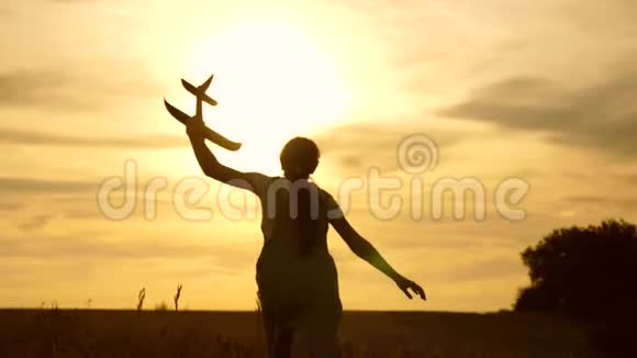 年轻女孩带着一架玩具飞机在田野上奔跑在阳光下孩子们玩玩具飞机青少年的梦想视频的预览图