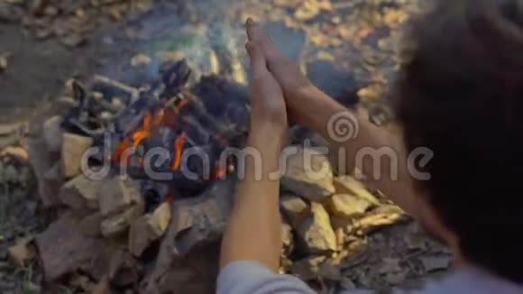 年轻人坐在寒冷的秋林中的篝火旁秋假概念视频的预览图