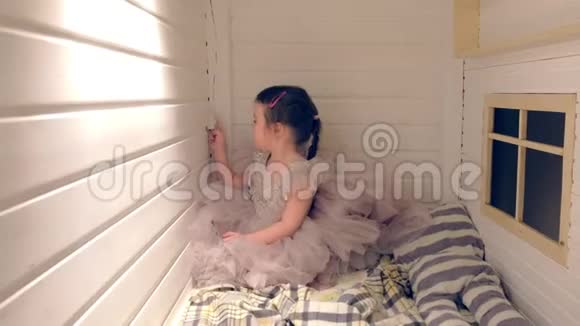 小女孩穿着一件漂亮的衣服坐在她床上的房子里灯光开着又开视频的预览图