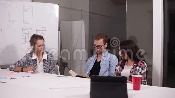 三个企业家或学生坐在一起在一个办公桌上工作比较文件做笔记年轻人视频的预览图