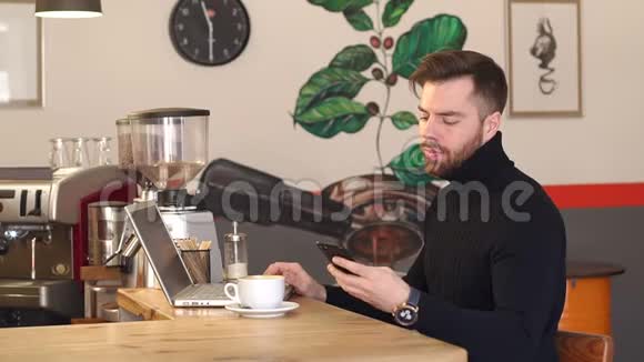年轻的商人带着笔记本电脑在咖啡店工作还在打电话视频的预览图